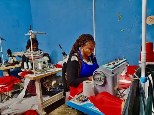 Two women working at sewing machines during a tailoring training session